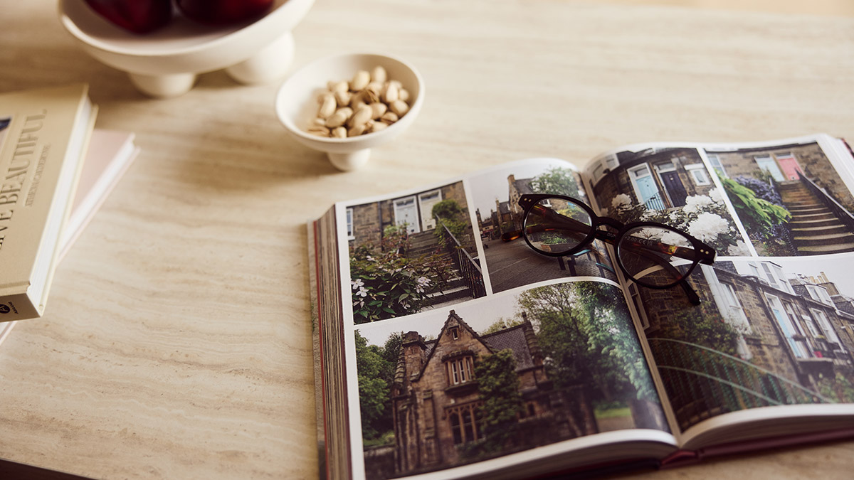 Open interior design magazine with architectural photography and glasses on a light marble coffee table