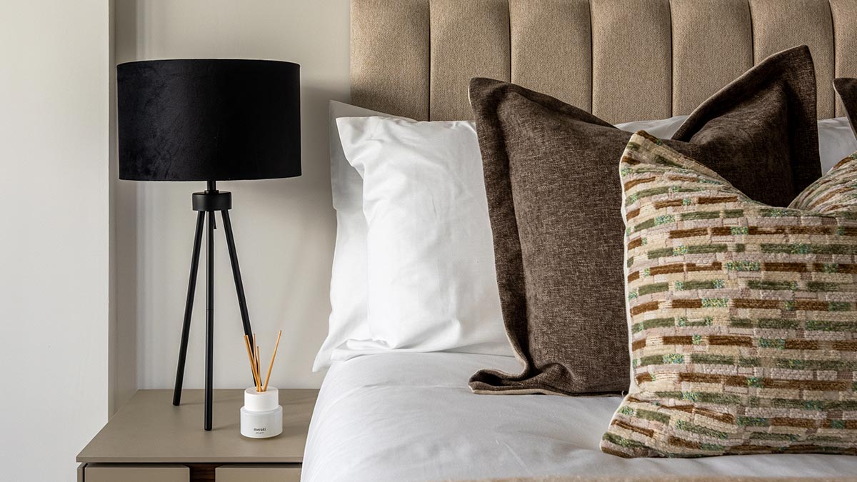 Luxury bedroom with neutral bedding, textured cushions and modern bedside lighting