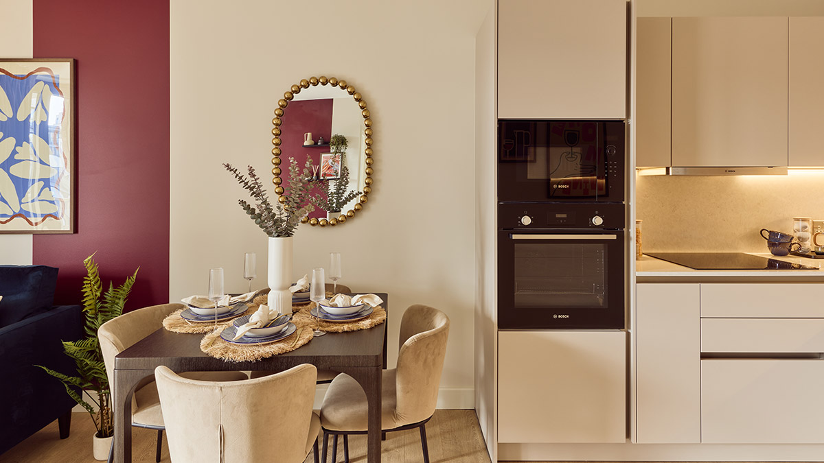 Modern apartment dining area with a styled dining table, upholstered chairs and a contemporary fitted kitchen