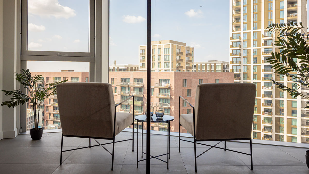 Modern apartment lounge with two armchairs overlooking the city skyline through floor-to-ceiling windows